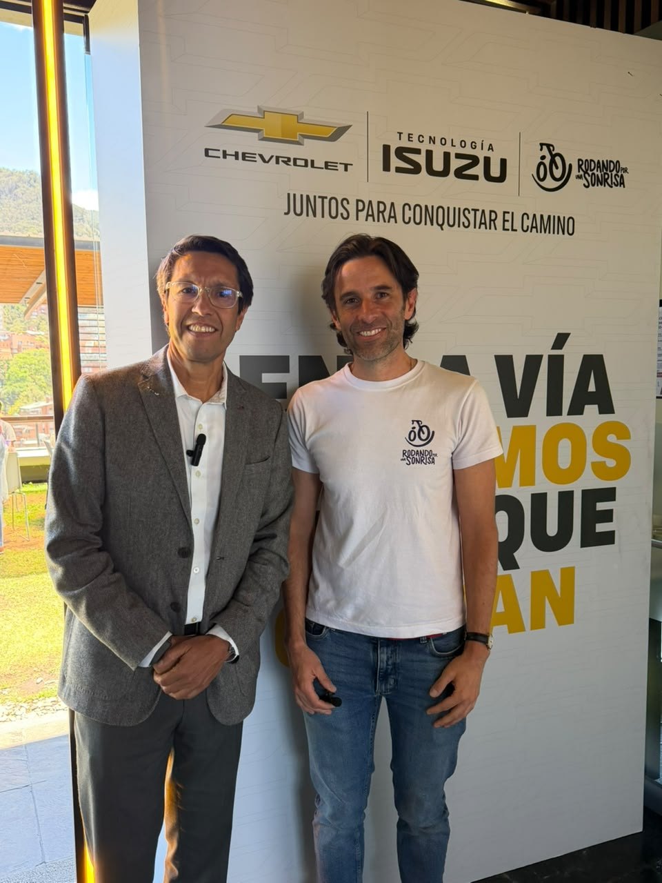 Dos representantes frente al panel Chevrolet, Tecnología Isuzu y Rodando por una Sonrisa