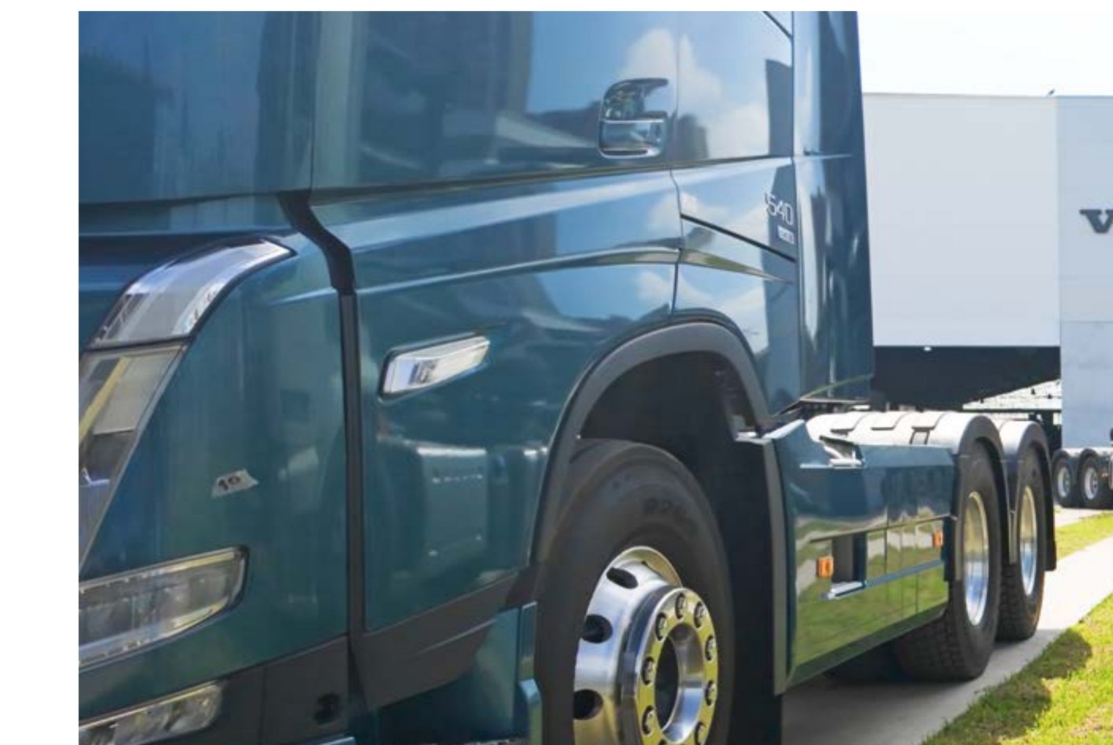Detalle de un tractocamión Volvo FH frente a una sede de la marca